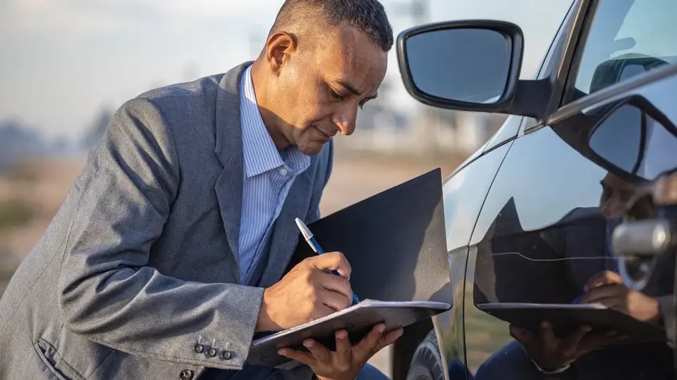 Minor car accident with an insurance agent taking notes while assessing the damage